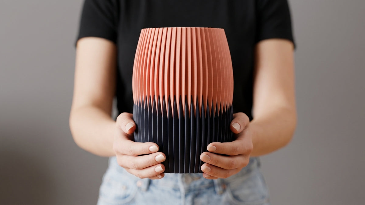 Interlock Vase in peach and charcoal held with both hands for scale.